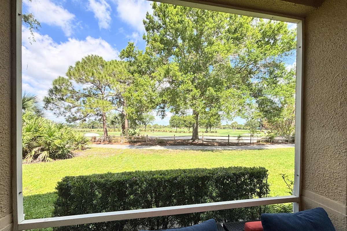 Peaceful outdoor view overlooking green space, mature trees, and a scenic walking path.