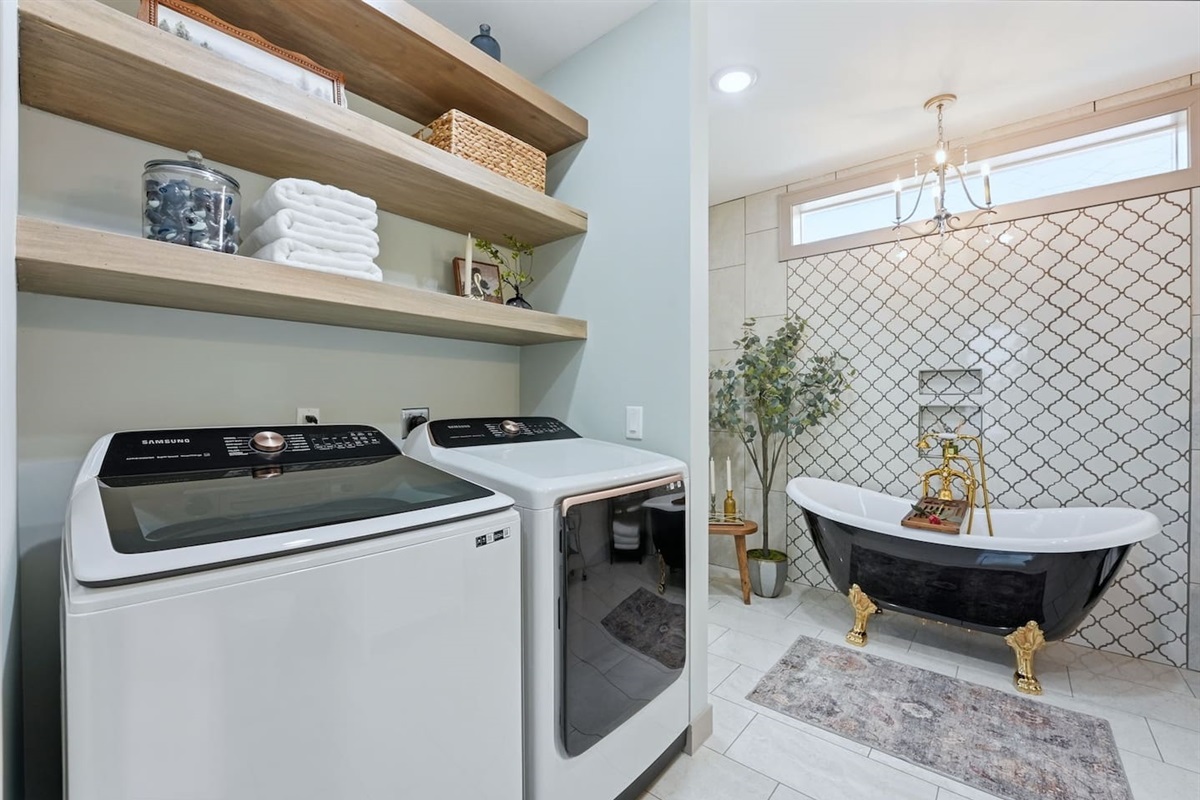 Convenient in-home laundry area with modern washer and dryer, open shelving, and fresh linens—perfect for extended stays and added comfort.