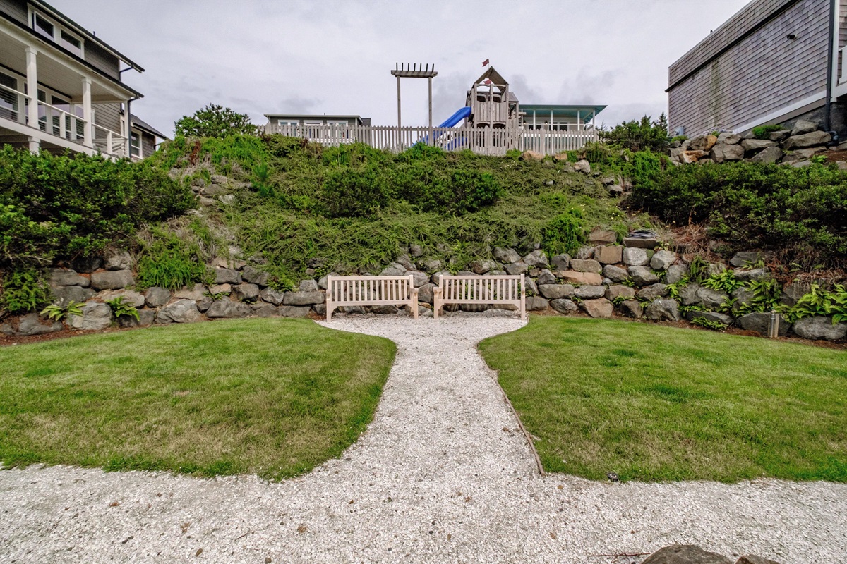 A peaceful garden path and seating area right beside the home—perfect for reading, picnicking, or enjoying the ocean breeze. 