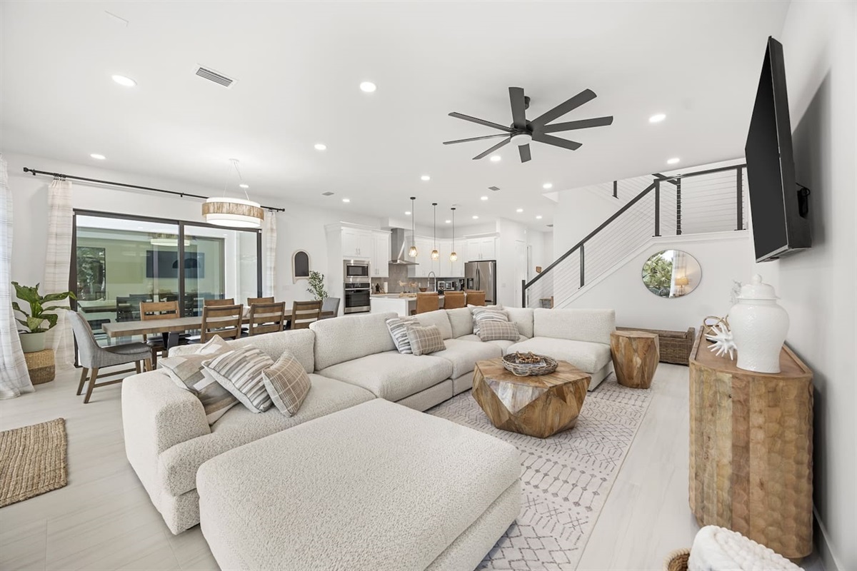 Luxury new build ocean front property featuring high-end finishes, an open kitchen, dining, and living room layout with a spacious sectional and warm wood accents.