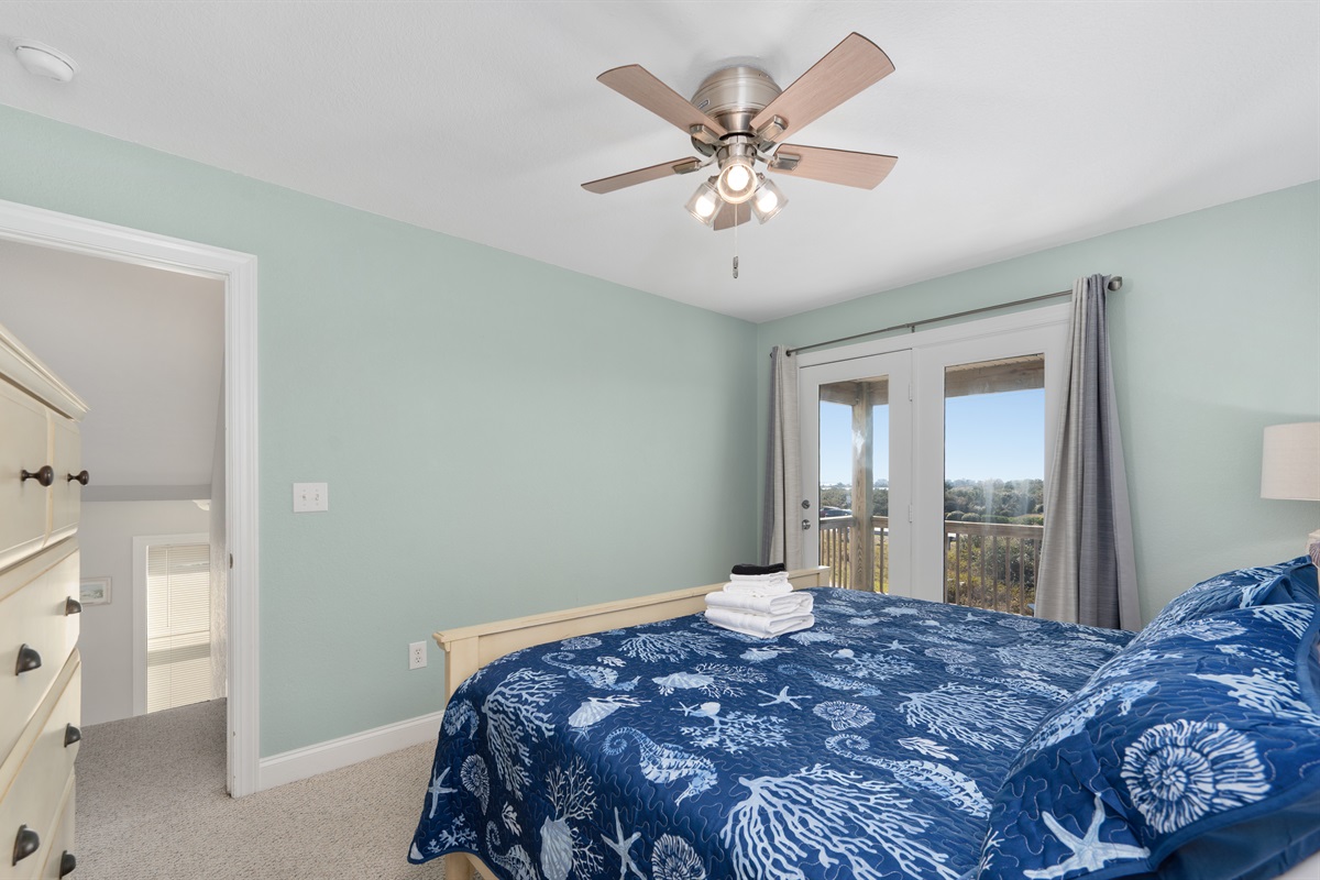 Spacious king bedroom featuring a ceiling fan, deck access, and a cozy place to unwind.