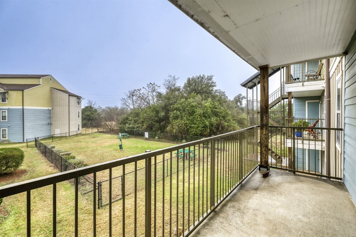 Peaceful balcony view overlooking a green, open courtyard.
