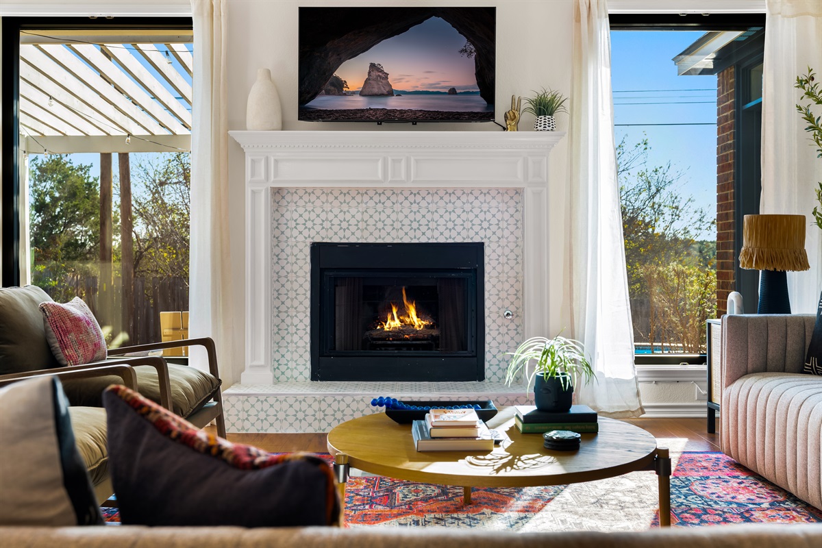 Centerpiece fireplace, surrounded by windows, casting a natural glow indoors.