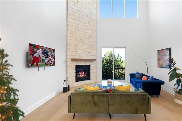 spacious living room with fire place, comfy couch, patio overlooking mountain and lake views