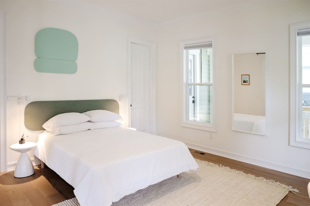 The downstairs bedroom is an airy oasis. Featuring custom art and headboard - the spacious room has a queen size bed, a walk-in closet, a desk for work-from-home, smart TV and direct access to a full bathroom.