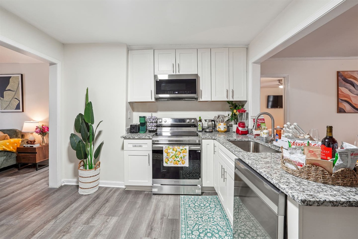 A fully equipped kitchen with a refrigerator, microwave, stove, oven,fridge, dishwasher, coffee maker, kettle, toaster, and blender. Includes plates, bowls, utensils, pots, and pans, plus four bar chairs for casual dining or socializing.
