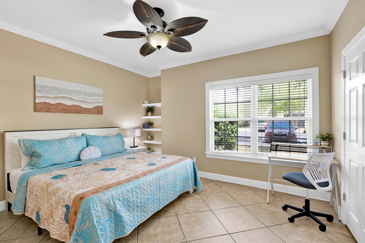 Primary bedroom with king bed, ceiling fan, wall mounted smart TV and en-suite bathroom 