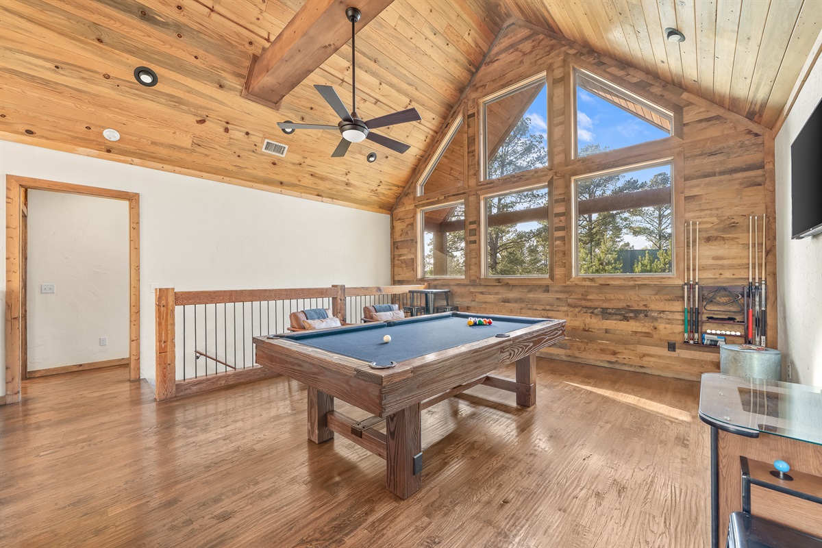 Game loft with pool/ping pong table, arcade table, and television.