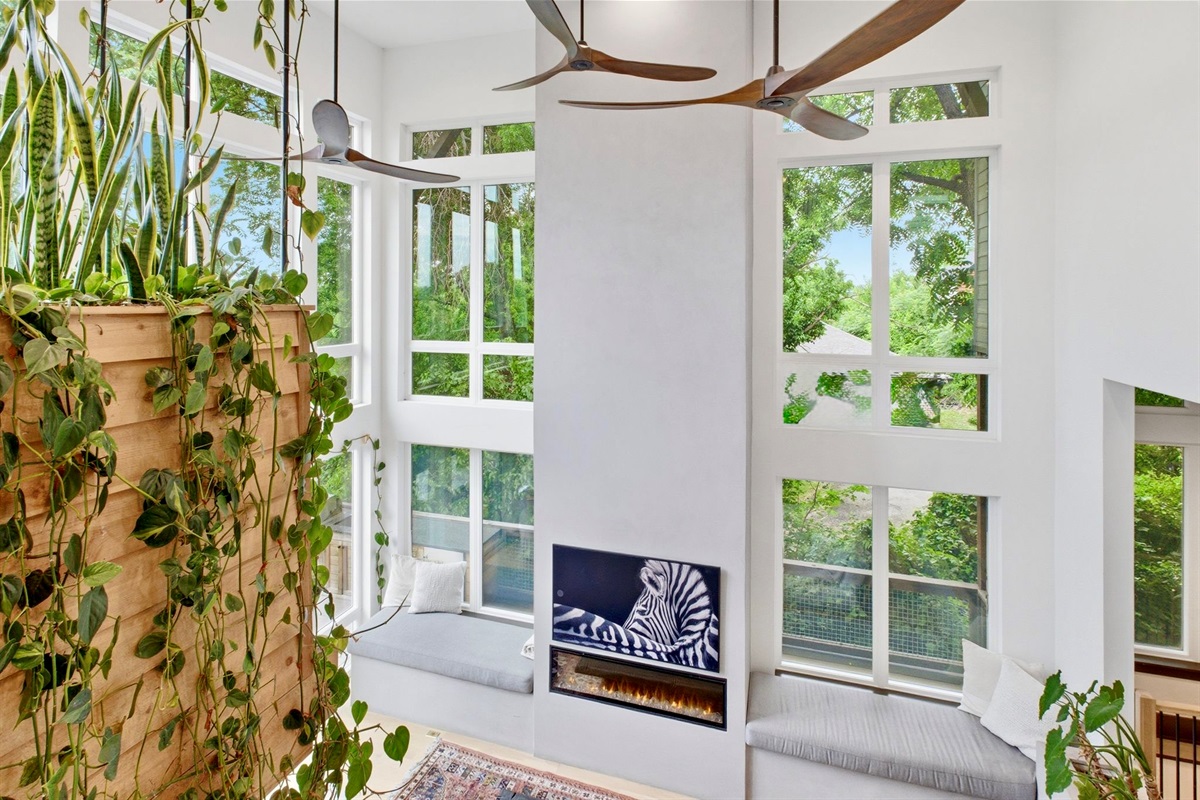 Tall arched windows frame the greenery outside, bathing this cozy reading nook in natural light.

