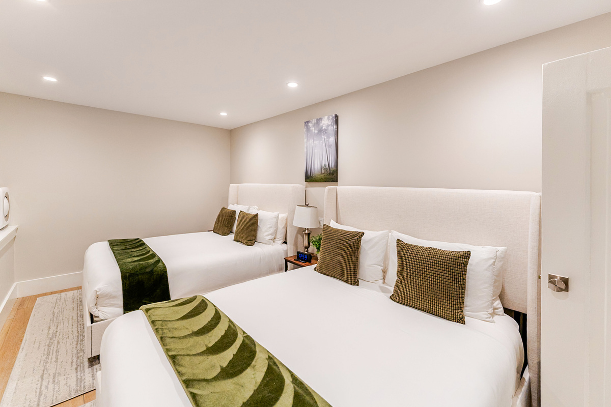 Large bedroom w/ 2 brand new Avocado Green queen beds & luxury bedding, 3 nightstands w/ built-in charging stations, built-in closet for storage & 65" NeoQLED 4k smart TV