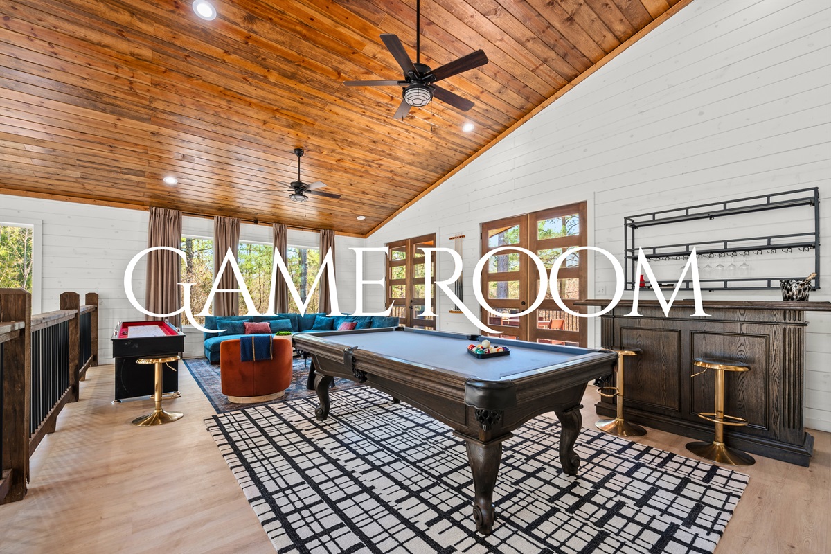 The game room is packed with entertainment, featuring a pool table, shuffleboard, and a bar for friendly competition and fun nights in.