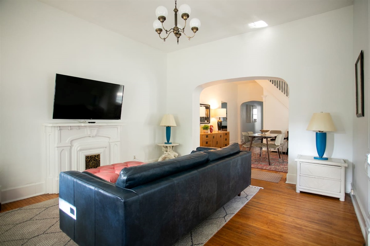 Full-length, deep-seated leather sofa facing a decorative fireplace and 55” Roku TV, with soft lighting, cozy blankets, and fast Wi-Fi for relaxed nights and easy streaming.
