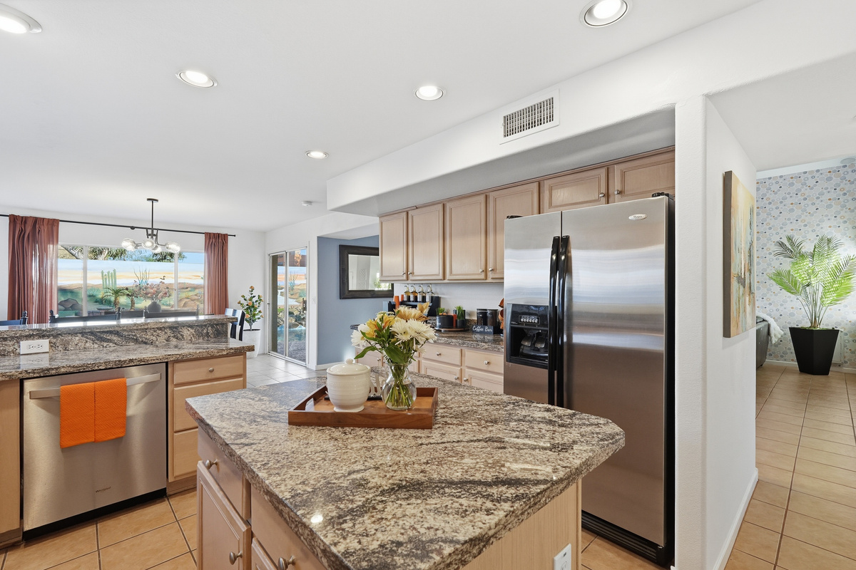 Full kitchen with granite island, appliances, dishwasher, and open flow to the dining and living areas.