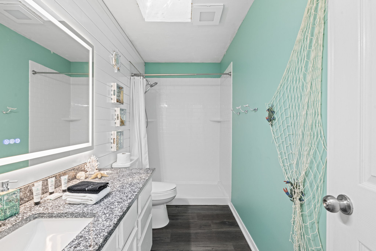 Coastal charm continues in the bath with a soft seafoam palette, fishnet accents, and plenty of counter space.