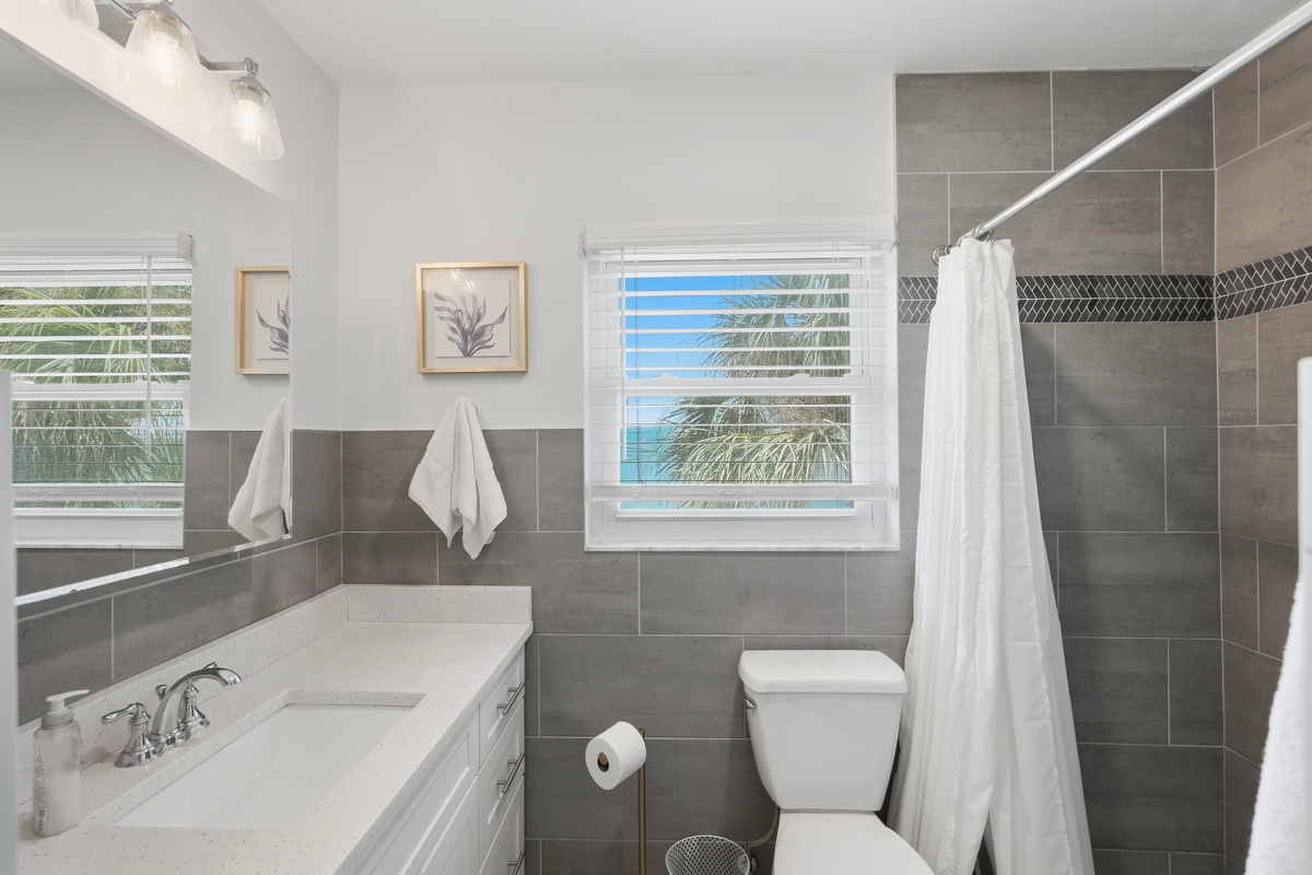 Connected to the primary bedroom, the ensuite bathroom offers a comfortable space to refresh and get ready for the day, with a bathtub, fresh towels, and essential amenities.