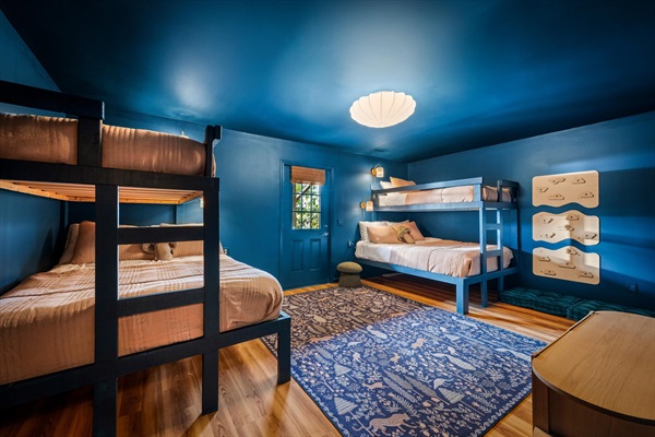 Bunk room with two twin-over-queen bunks, climbing wall, and smart TV—a fun space where kids can hang out, play, and make their own memories.