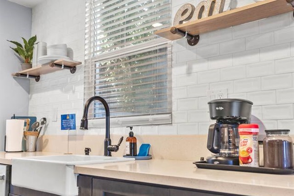 Enjoy the perfect blend of style and practicality in our kitchen, featuring a sleek sink, efficient dishwasher, and coffee maker. A cheerful plant brings life to the space, making it a great spot for cooking and relaxation.