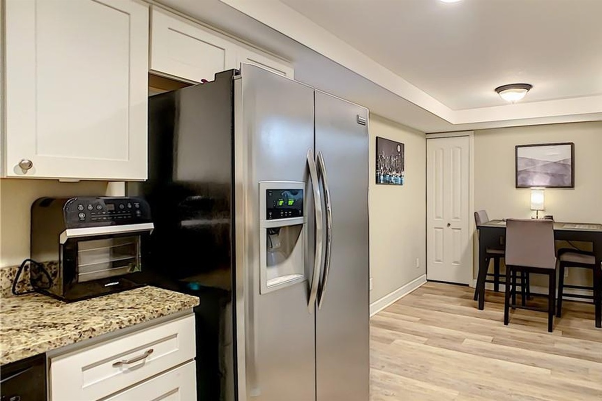 Fully-stocked kitchen featuring stainless-steel appliances, full-size refrigerator, and breakfast bar—cook fresh seafood from John's Pass and enjoy midterm stays near Madeira Beach in Seminole.