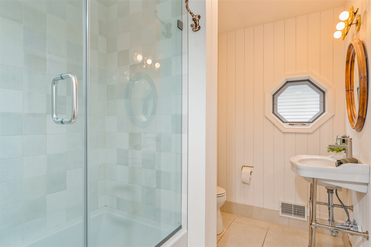 Spa-inspired main floor bathroom featuring a sleek glass shower, octagon window, and bright modern finishes — perfect for a refreshing start to your day.