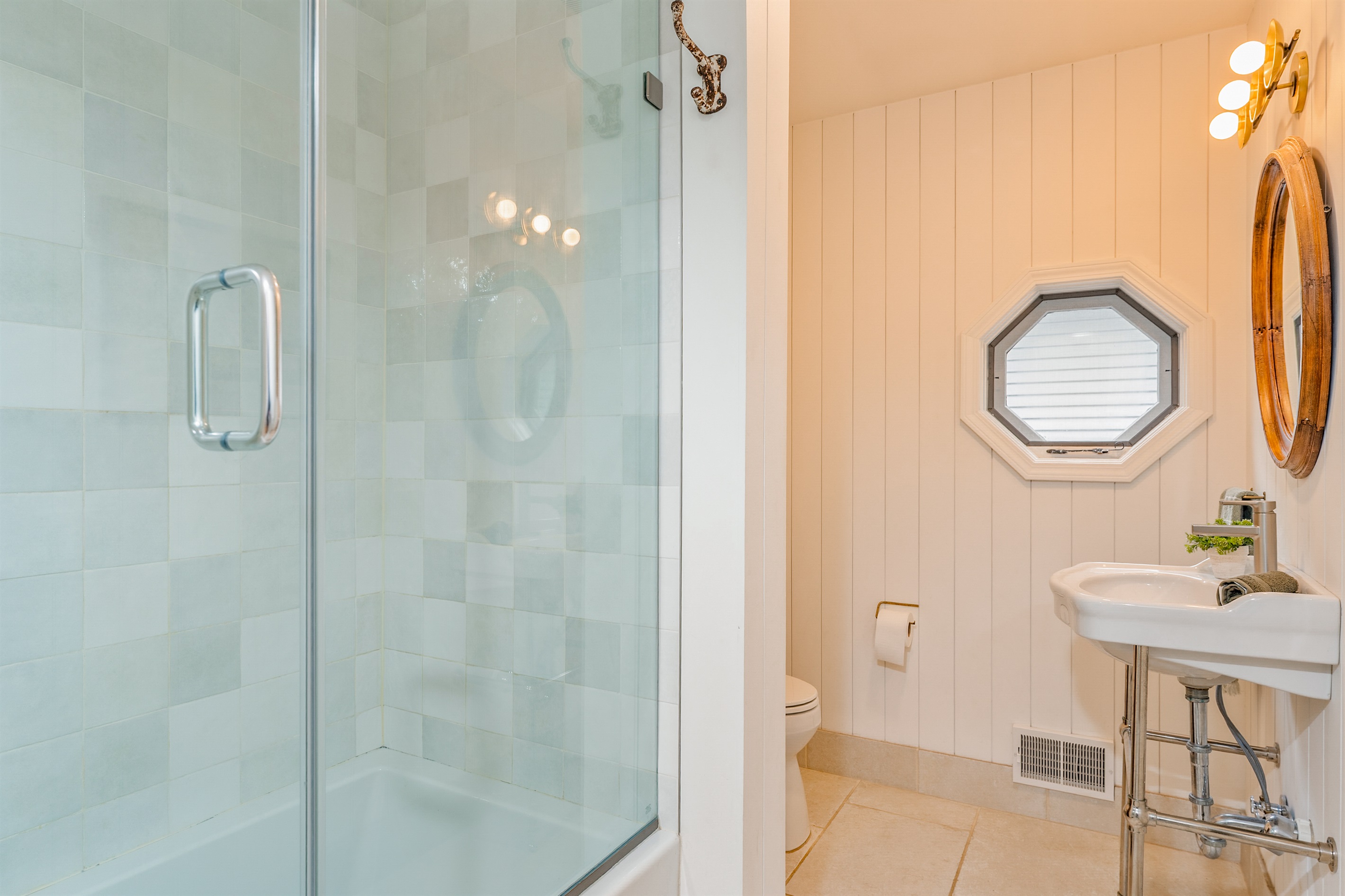 Spa-inspired main floor bathroom featuring a sleek glass shower, octagon window, and bright modern finishes — perfect for a refreshing start to your day.