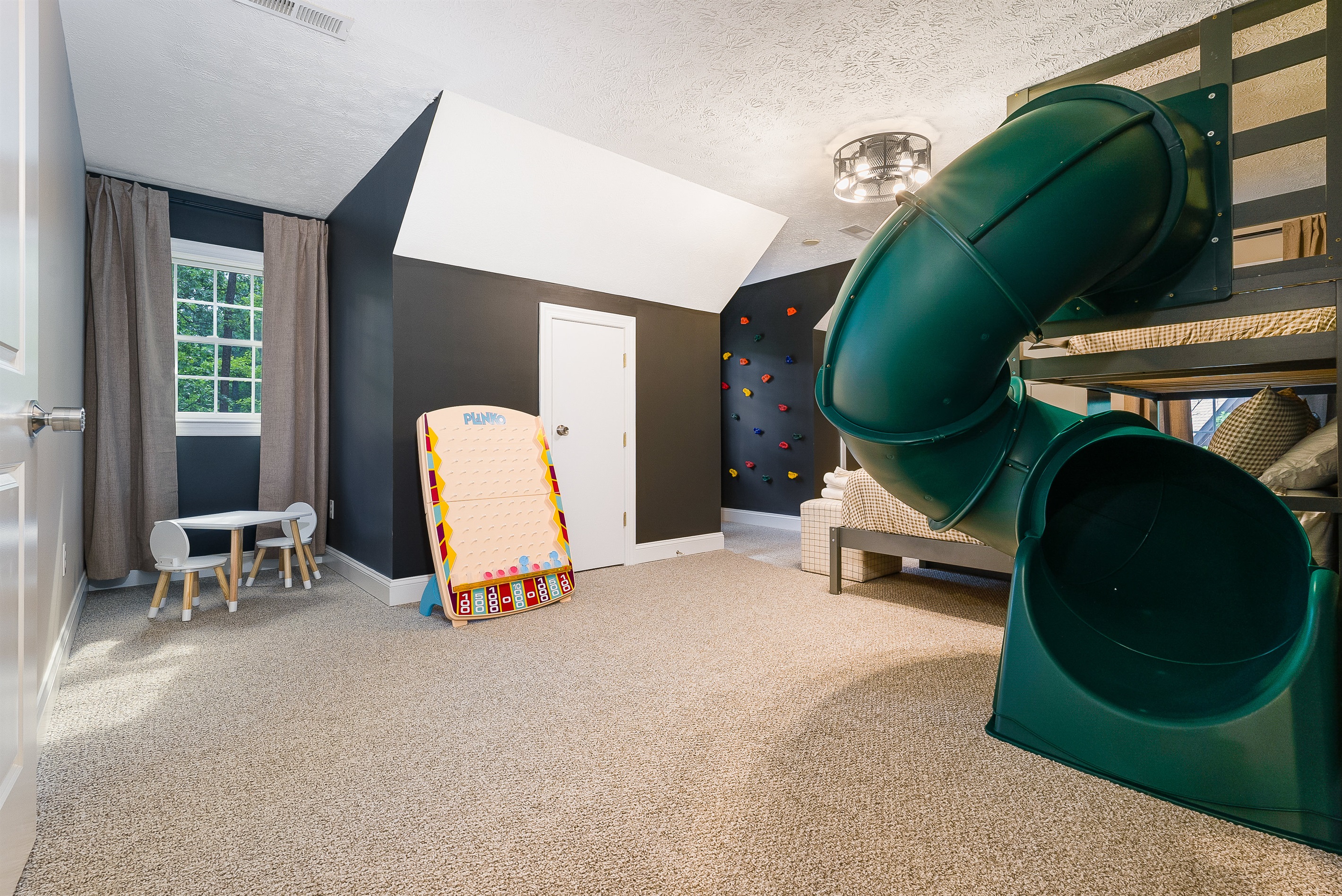 Kids will never want to leave this adventure-themed bunk room with double bunks, a tube slide, rock wall, and play table.