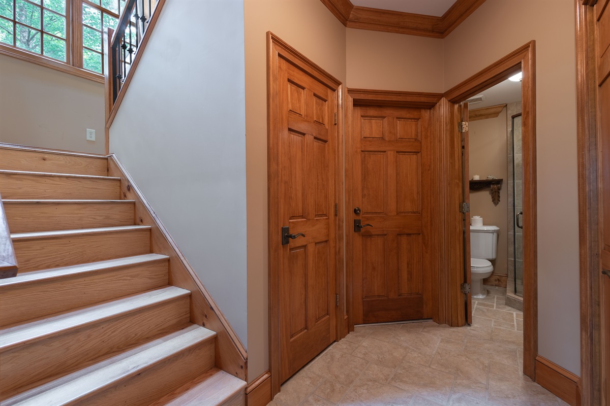 The lower-level hallway provides access to the bathroom, storage areas, and stairs leading to the main level above.