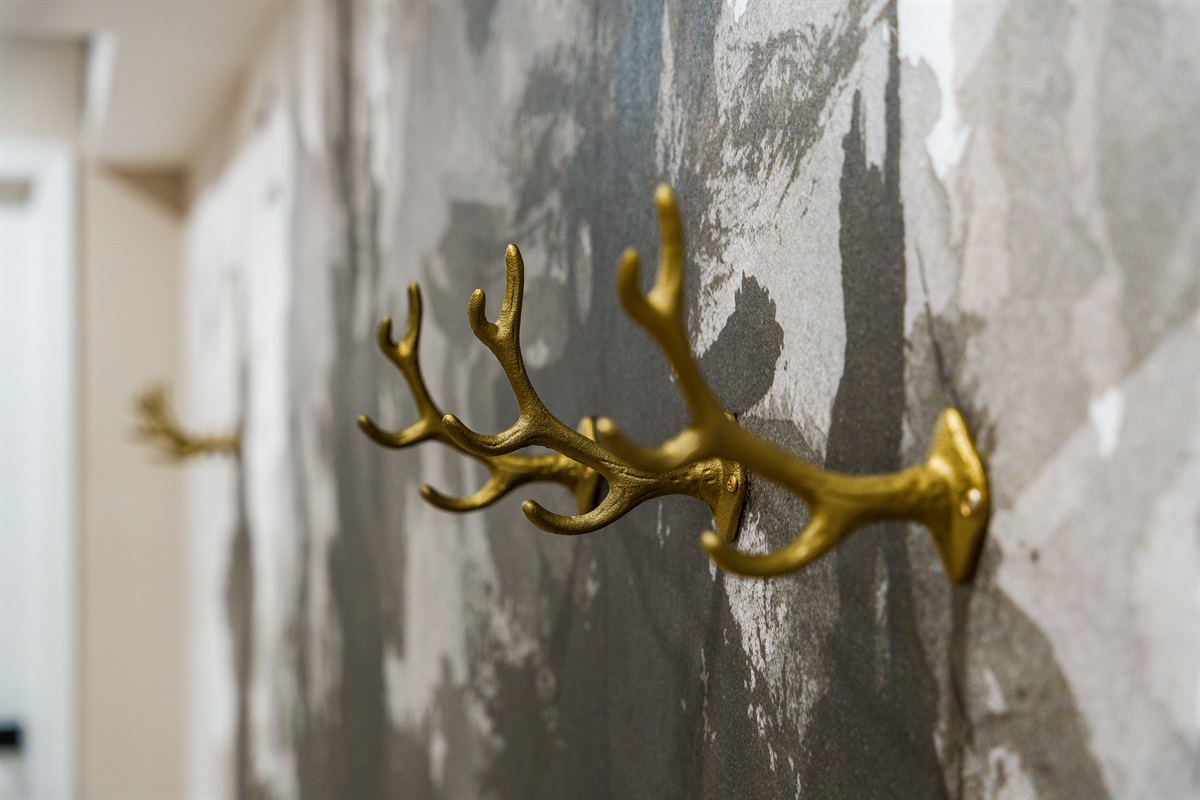 Golden antler hooks add a touch of rustic charm and function, blending perfectly with the mountain-inspired theme while offering a convenient spot to hang coats or gear.