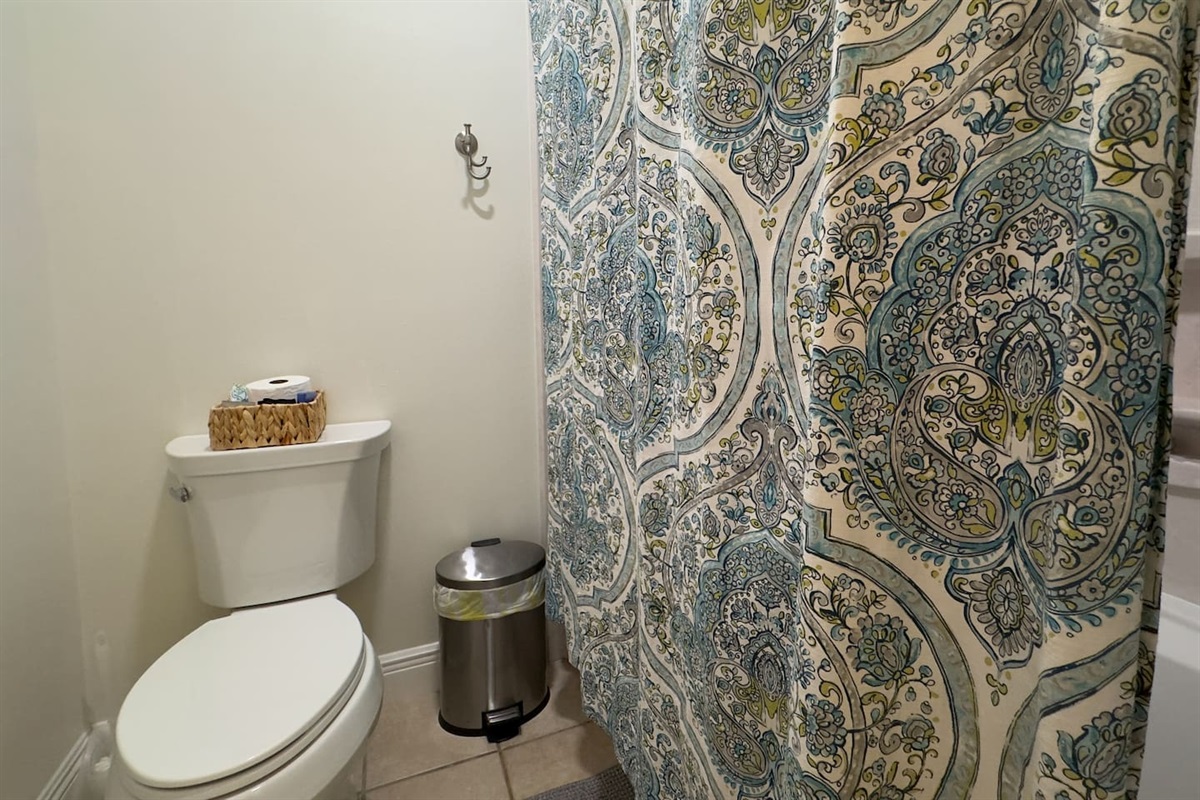 A neatly arranged bathroom with a white toilet and decorative shower curtain creates a welcoming space.