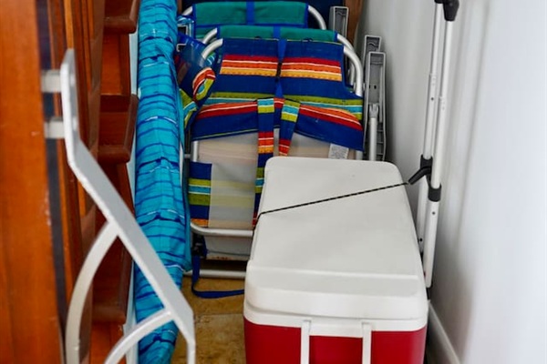 Beach gear ready to go: folding chairs, umbrella, rolling cooler, beach towels, and various beach toys