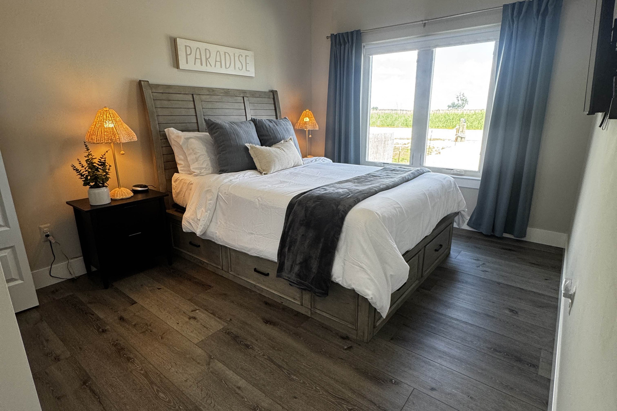 Cozy bedroom featuring a comfortable bed with neutral tones, soft lighting, and large windows offering natural light and peaceful outdoor views—perfect for a relaxing stay.