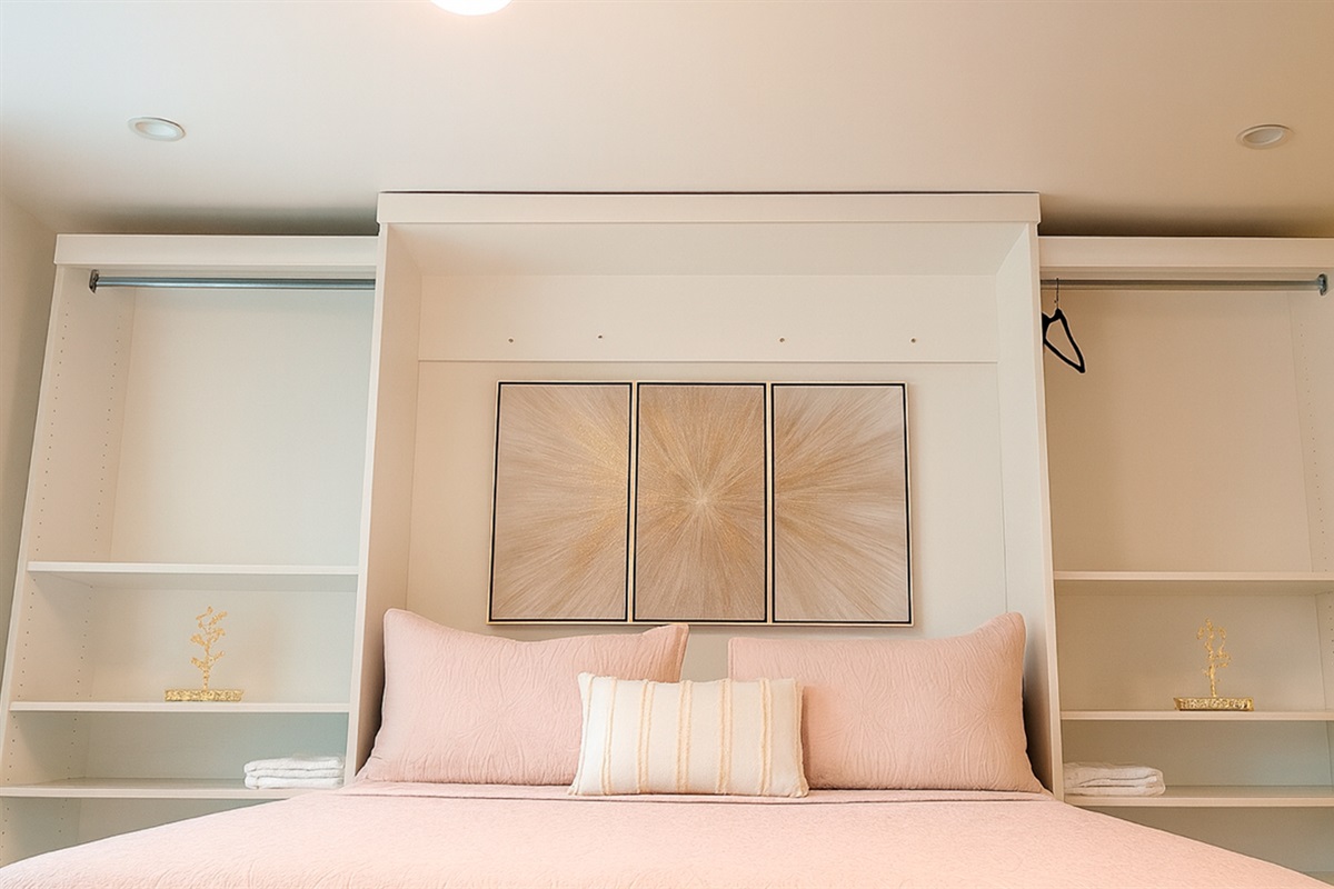Cozy sleeping area in The Gold Room, with textured bedding, gold artwork, and open shelving for a clean, modern feel.