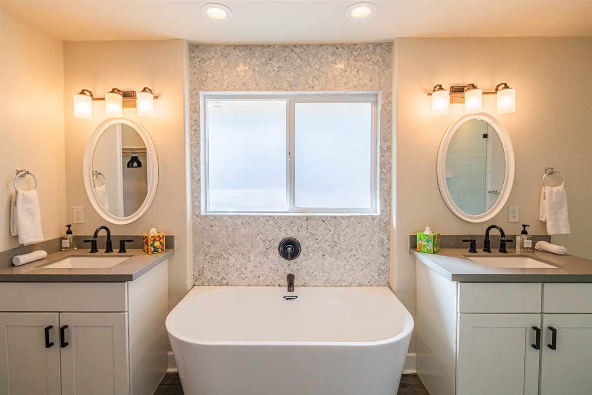 Spa-style bathroom featuring a soaking tub, double vanity, and stylish finishes — perfect for unwinding and recharging during your stay.