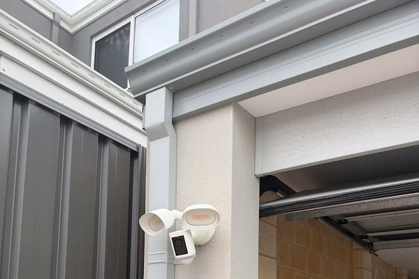 Self check-in via key lockbox at the garage, with an exterior security camera and floodlight covering the entry
