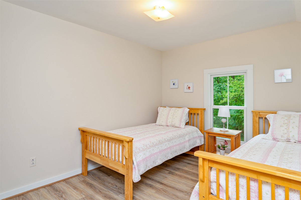 Cozy twin bedroom with fresh décor and wooded views, offering comfort and tranquility for guests of all ages. Bedroom #3 double twin beds