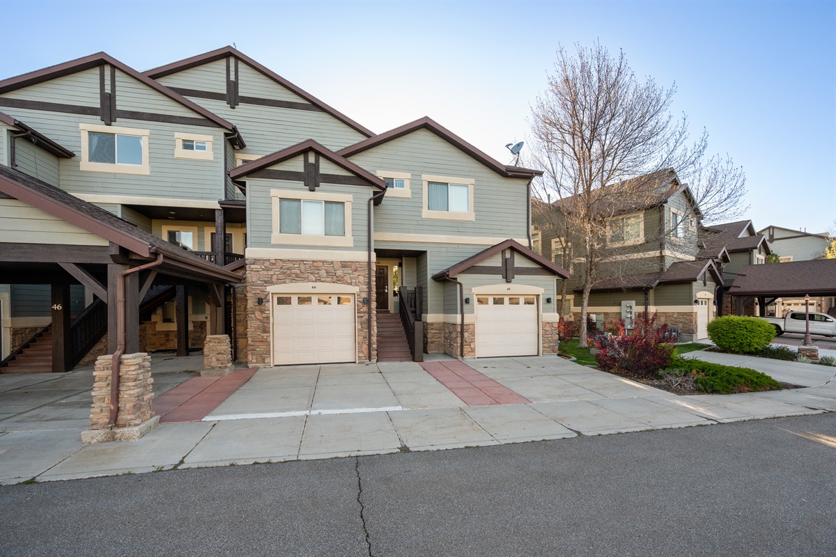 Charming townhome exterior with garage parking in a scenic mountain setting.