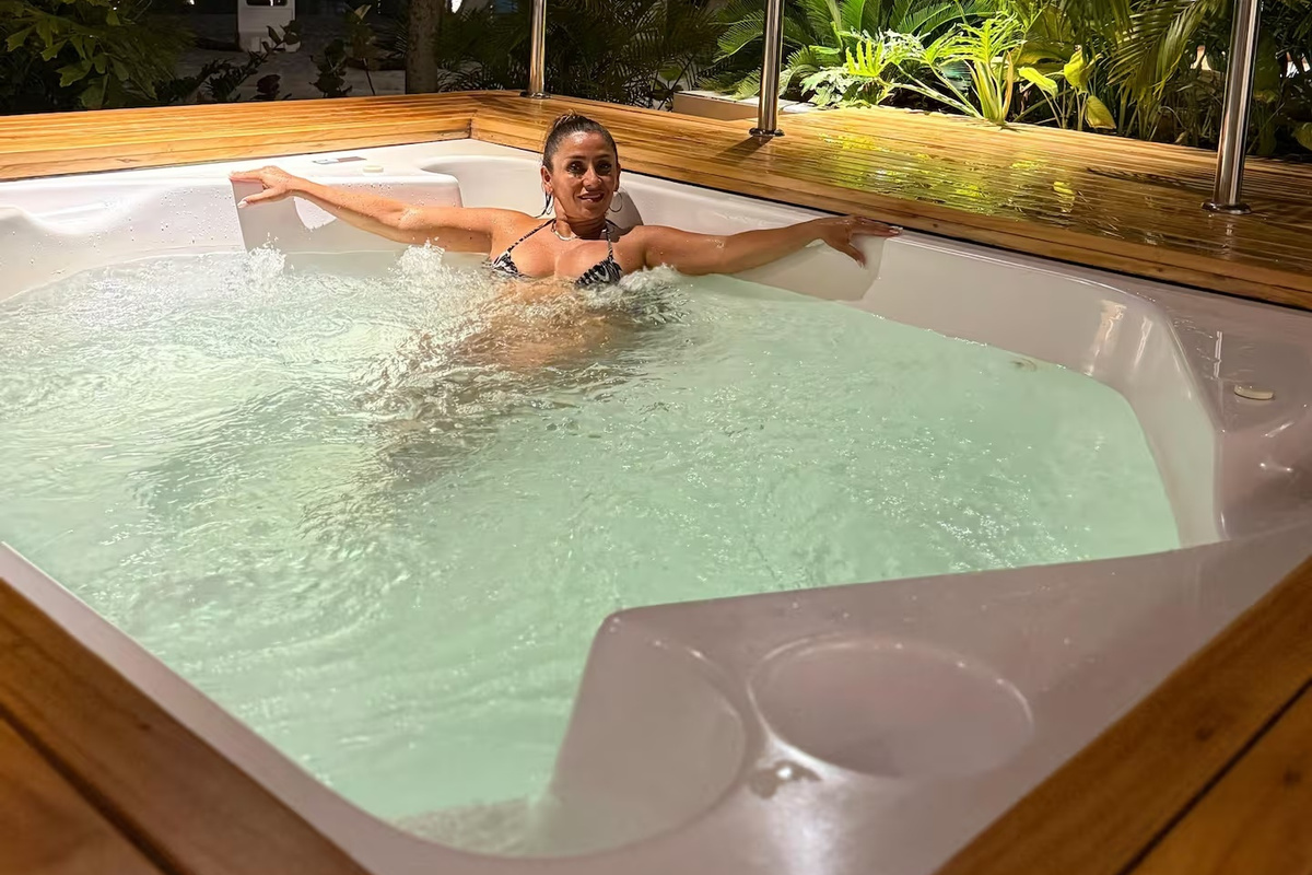 El spa crea un ambiente tranquilo tipo resort, con agua suavemente iluminada, acabados en madera y vegetación que refuerzan la sensación relajada de vacaciones.