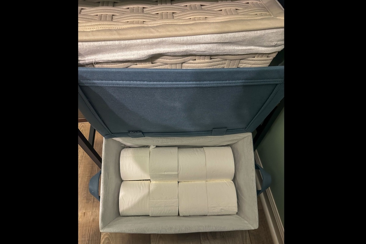 Half bath storage thoughtfully stocked with extra toilet paper for guest comfort and convenience.