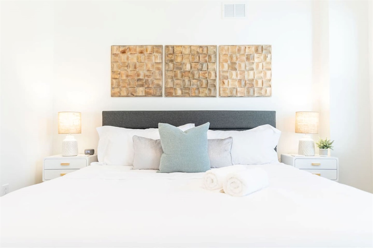 Zoomed-in view of the king-size bed with cozy pillows and lamps on each side, creating a warm and inviting atmosphere.