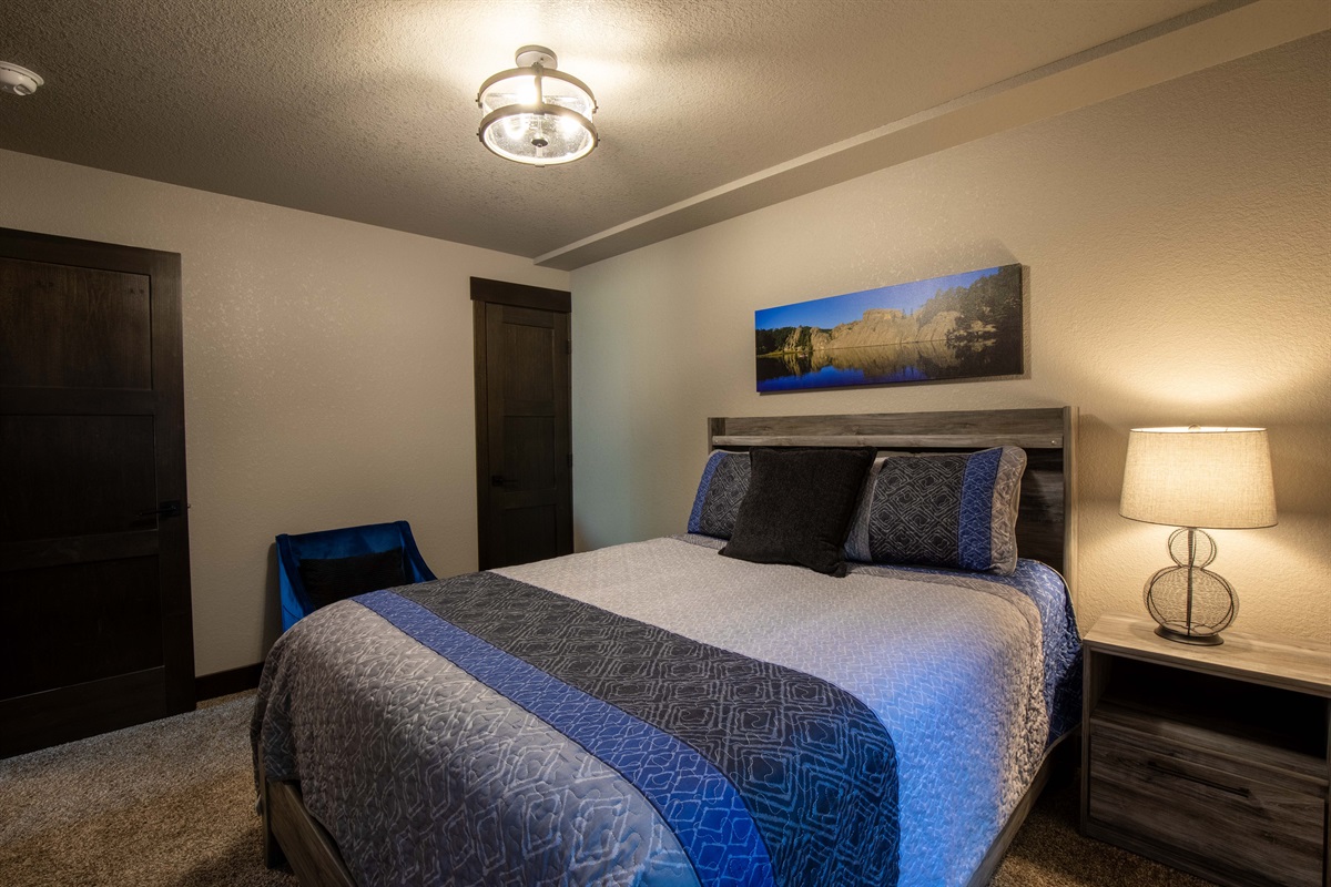 Relax in this cozy lower-level queen bedroom—perfect for guests seeking a quiet, private space to unwind after a full day of Black Hills adventure.