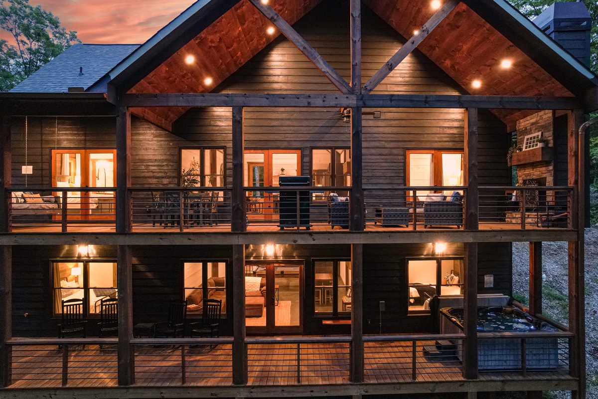 There are two levels of decks on the back of the house.  The back is surrounded by trees.  The top deck has a grill, dining area, large bed swing, and wood fireplace with seating area.  The lower deck has the 8 person hot tub and rocking chairs.