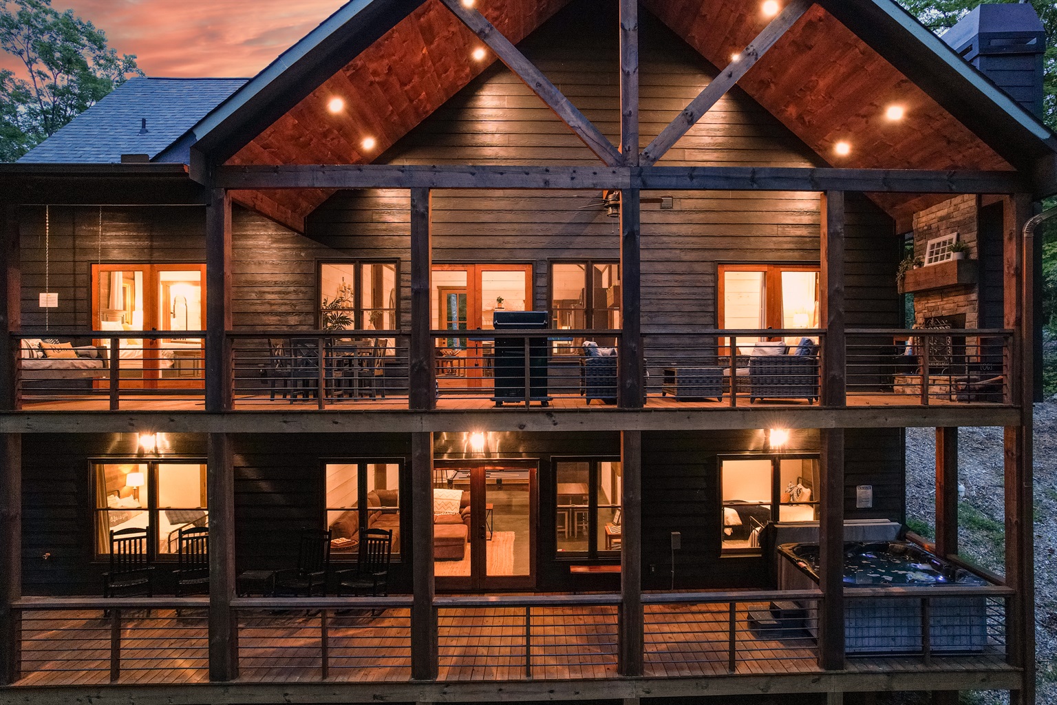 There are two levels of decks on the back of the house.  The back is surrounded by trees.  The top deck has a grill, dining area, large bed swing, and wood fireplace with seating area.  The lower deck has the 8 person hot tub and rocking chairs.