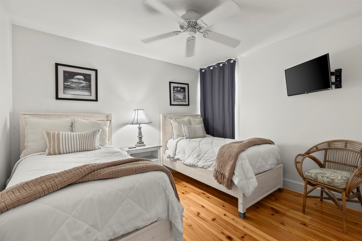 Welcome guests to the cozy guest bedroom in our Cotton Bayou condo, featuring twin beds with comfortable bedding and a charming coastal decor. Perfect for family or friends, this space ensures a restful stay in your home away from home.