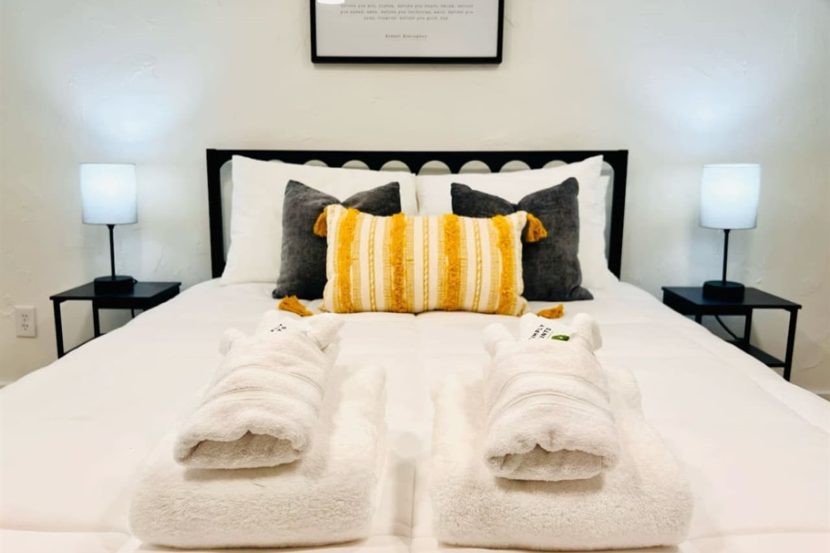 Queen sized bed with fresh sets of towels. 