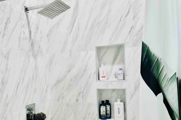 This upstairs bathroom continues the theme of white marble. Rainfall showerhead in this shower/tub combination.