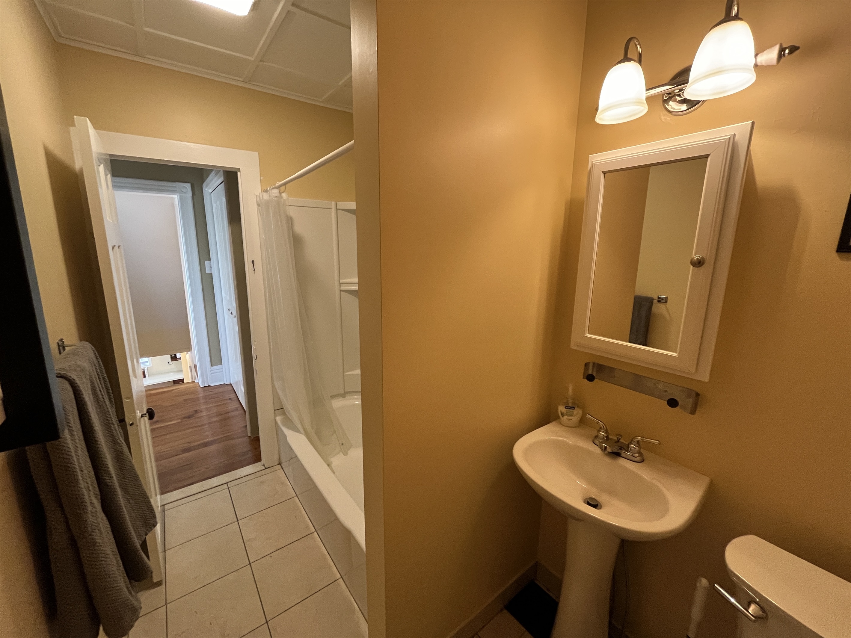 Cooperstown Cottage 2nd floor full bathroom with tub/shower combo view into the hallway.