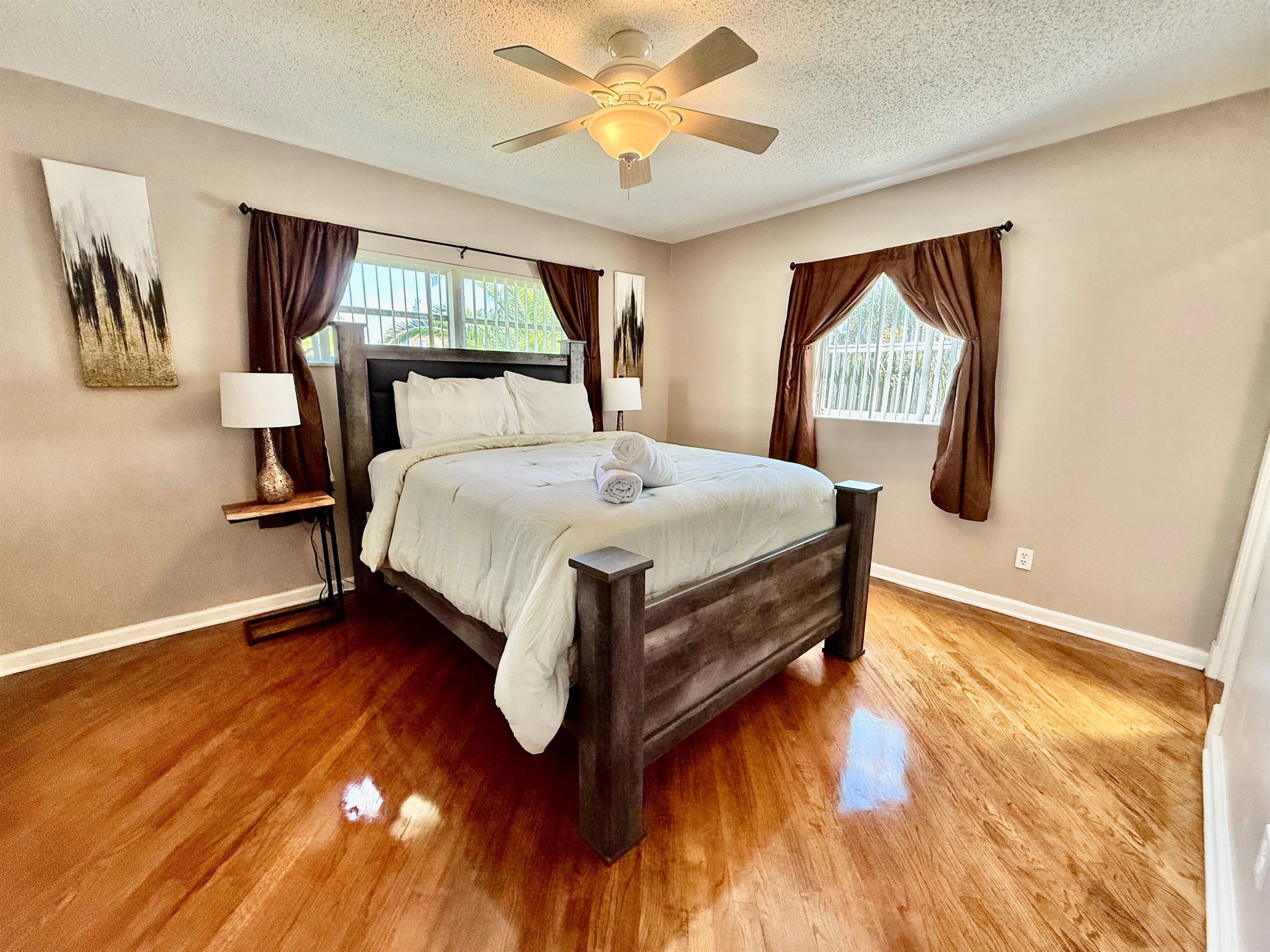 Unwind in this serene space, complete with soft bedding, blackout curtains, and natural light streaming in from multiple windows.