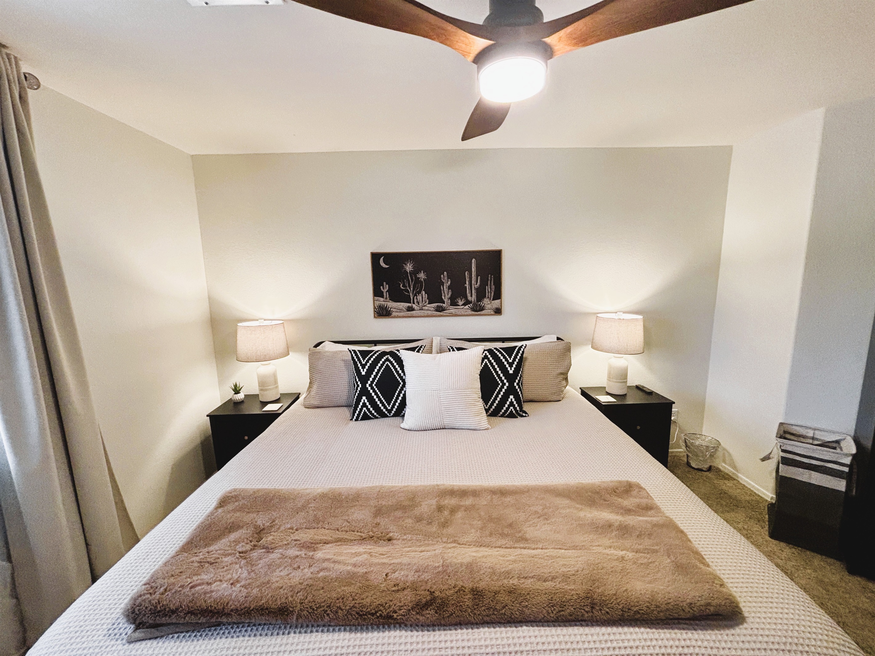 Bedroom with king bed, smart TV, ceiling fan, blackout curtains and linens