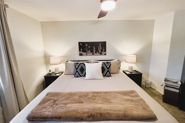 Bedroom with king bed, smart TV, ceiling fan, blackout curtains and linens