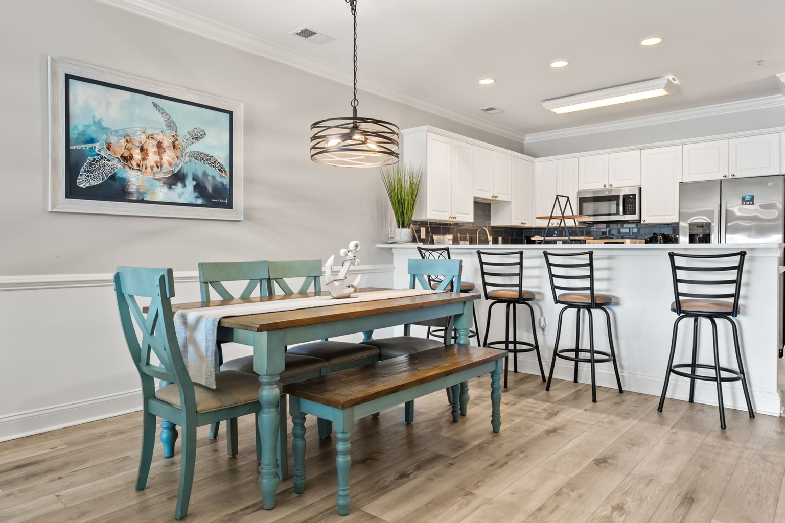 Spacious living room with comfy sofas, a beautiful coastal wooden dining table, modern fixture for natural light, and a serene theme—creating a cozy, elegant space perfect for relaxation and dining.