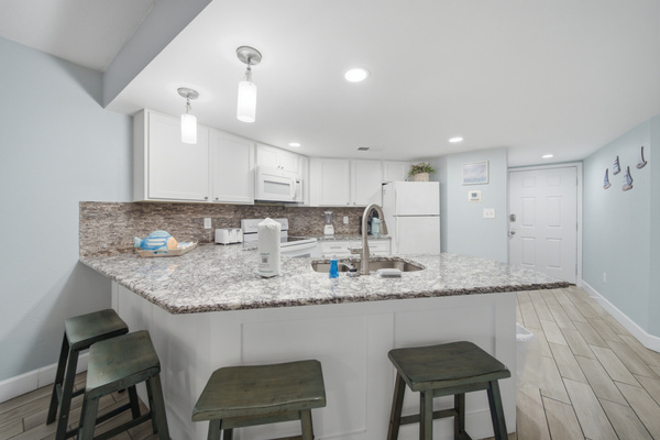 Kitchen island with granite counters and barstool seating for three